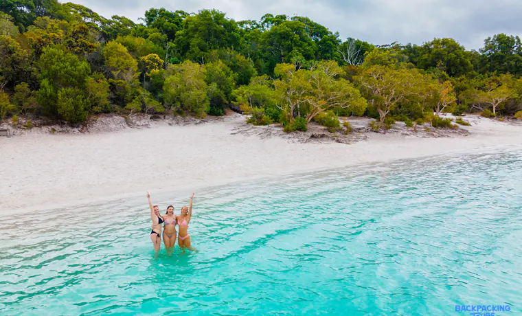 Three happy women celebrating in the crystal-clear turquoise waters of Lake Mackenzie, Fraser Island.