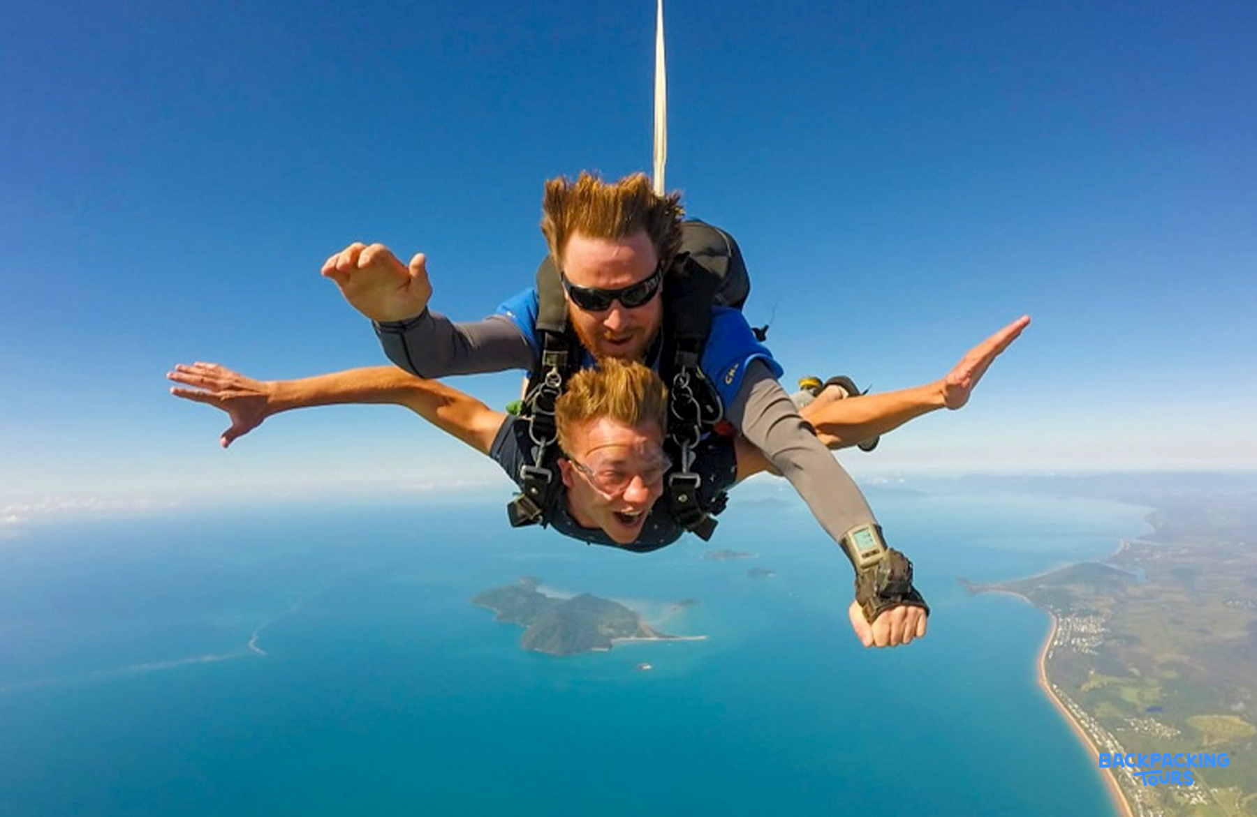 Two excited skydivers freefall high above the stunning coastline and blue ocean at Mission Beach.