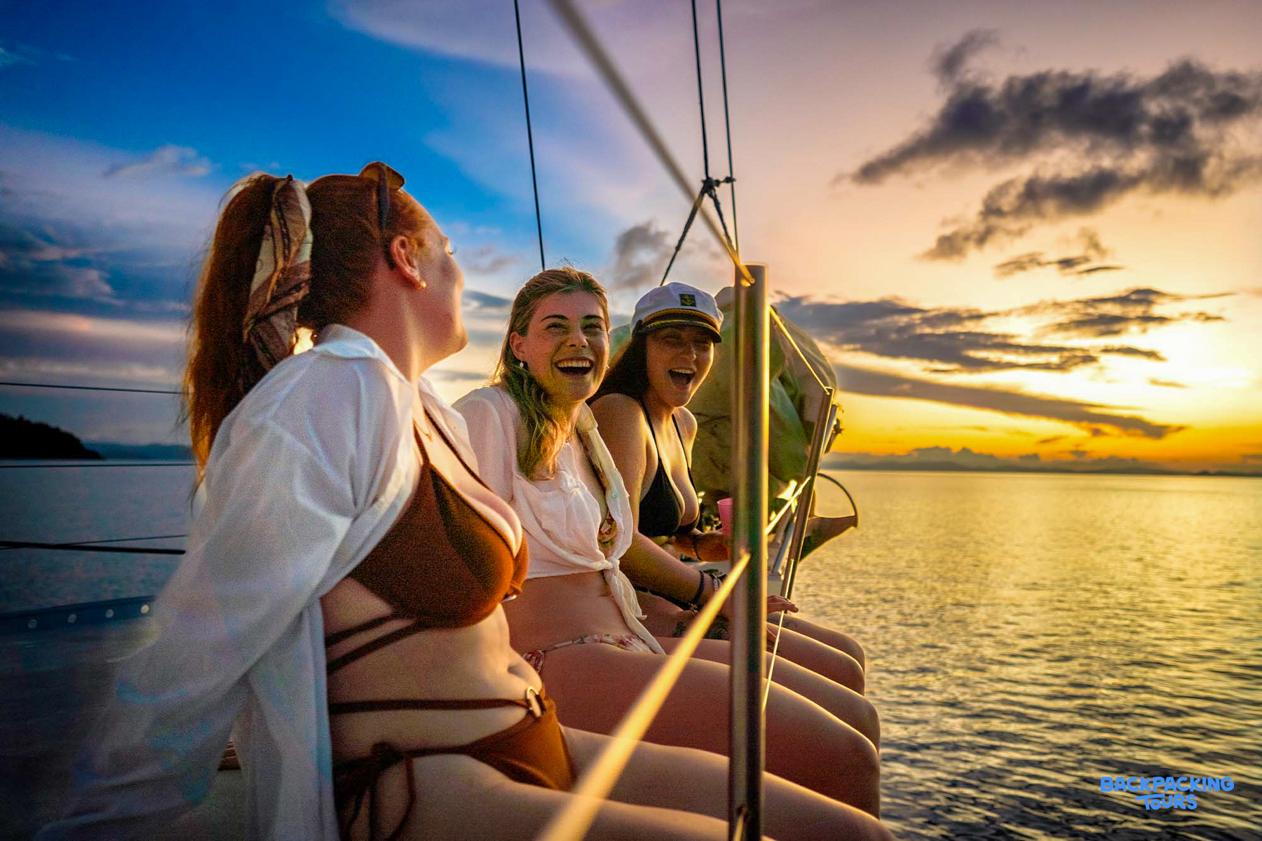 Three happy women enjoy a beautiful sunset sail on a boat in the Whitsundays.