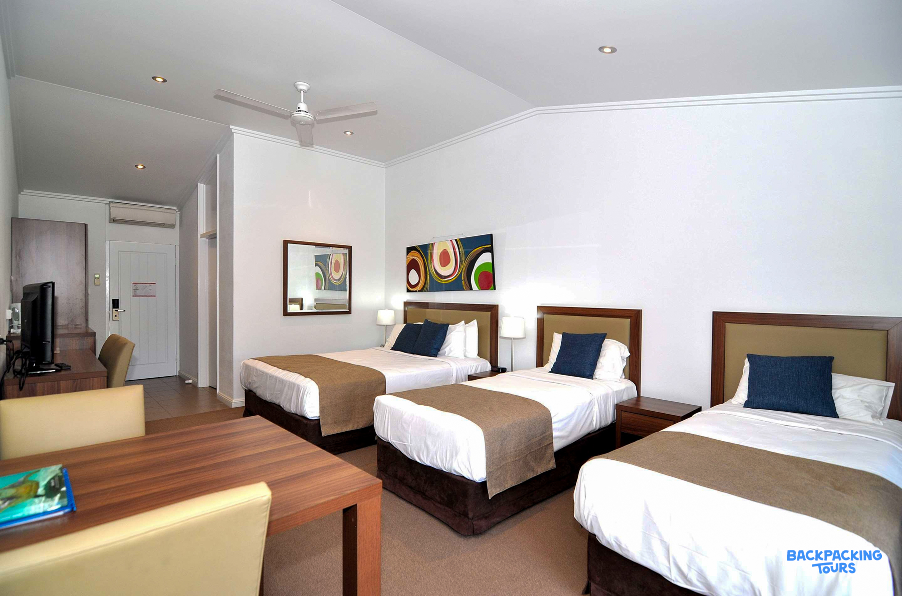 A bright triple room with three comfortable single beds at Mission Beach accommodation.