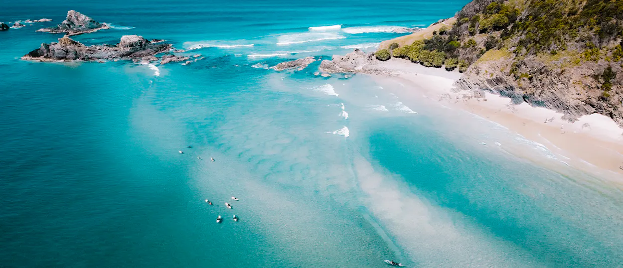 Aerial view of surfers waiting for waves in the clear turquoise waters of Byron Bay.