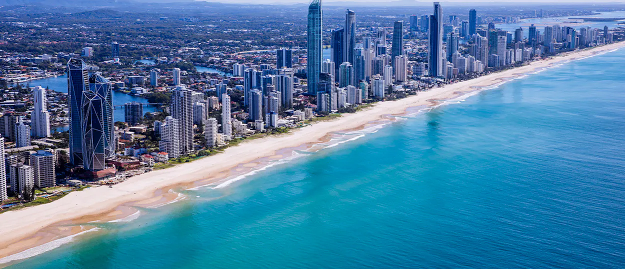 Aerial view of Surfers Paradise showcasing its golden beach, turquoise ocean, and a vibrant city skyline.