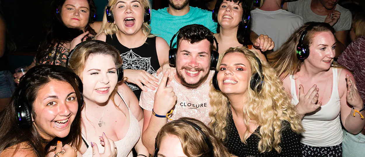 A group of happy young backpackers wearing headphones, enjoying a silent disco in Sydney.