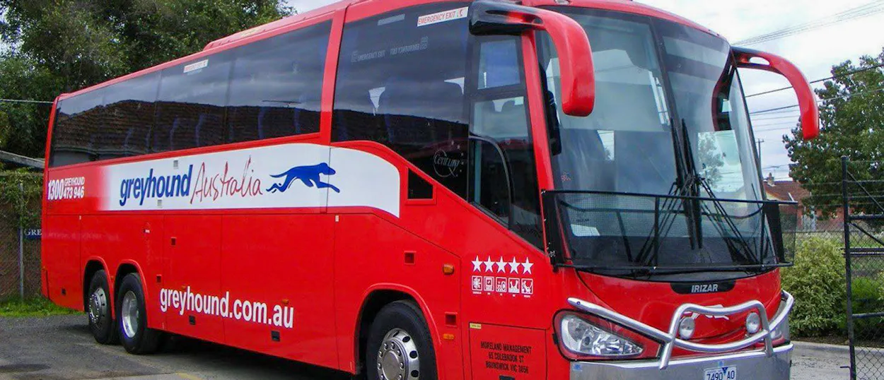 A large red Greyhound Australia coach bus parked outdoors, ready for its next journey.