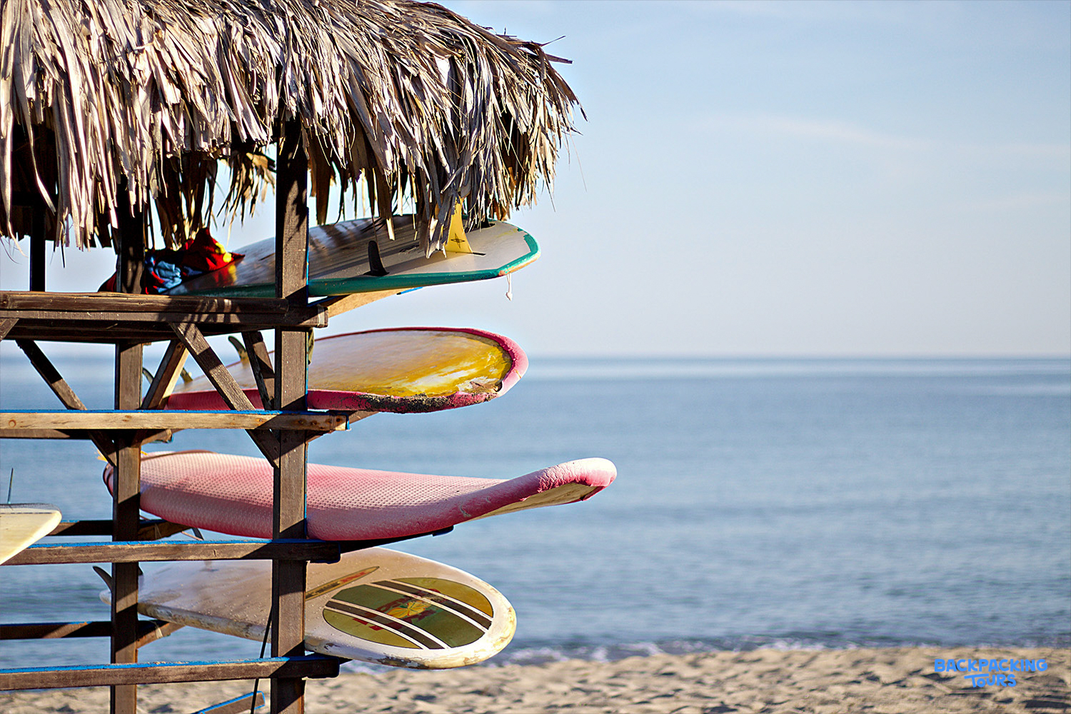 Colorful surfboards stored under a thatched hut on the sunny sandy beach of Byron Bay.