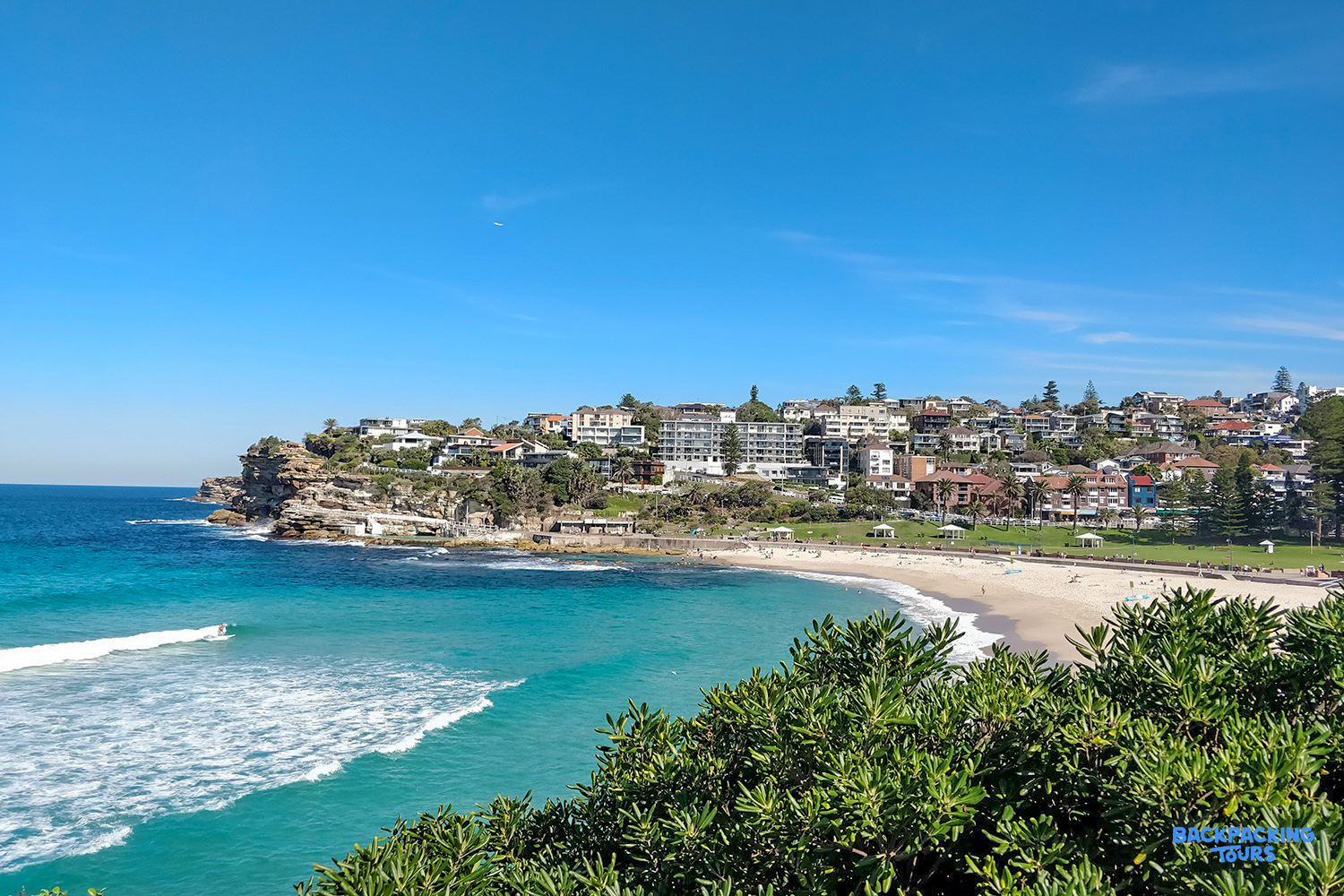 Panoramic views of Coogee Beach in Sydney, with golden sand, turquoise water, and coastal homes.