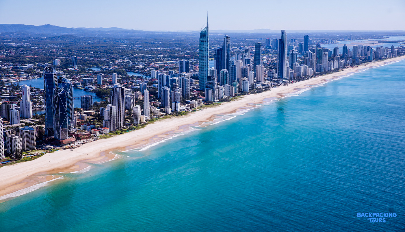 Aerial view of Surfers Paradise, Gold Coast, with a long golden beach and towering skyscrapers.