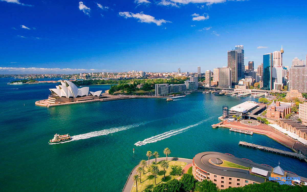 Boats cruise across Sydney Harbour, past the iconic Opera House and a vibrant city skyline.