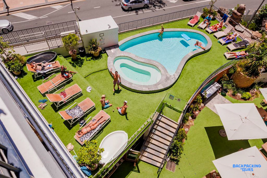 Guests relax by the pool and sunbathe on the artificial grass at a hostel in Surfers Paradise.
