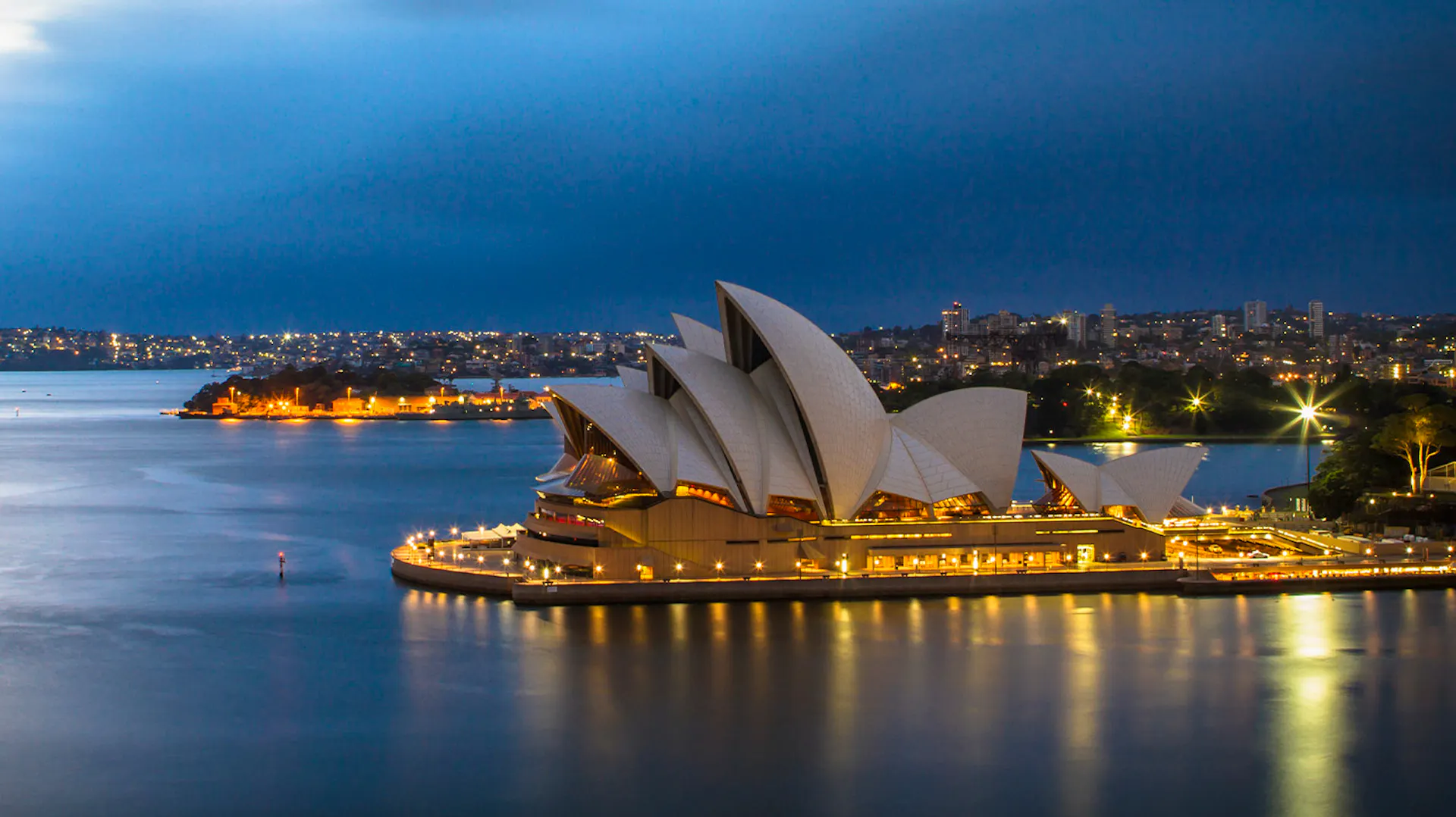 The iconic Sydney Opera House glows brilliantly at dusk, reflecting its unique architecture on the harbour.