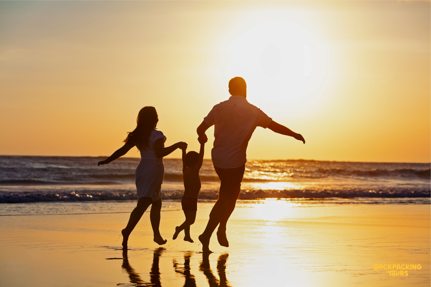 Happy family enjoying a golden sunset run on the beautiful Seminyak beach in Bali.