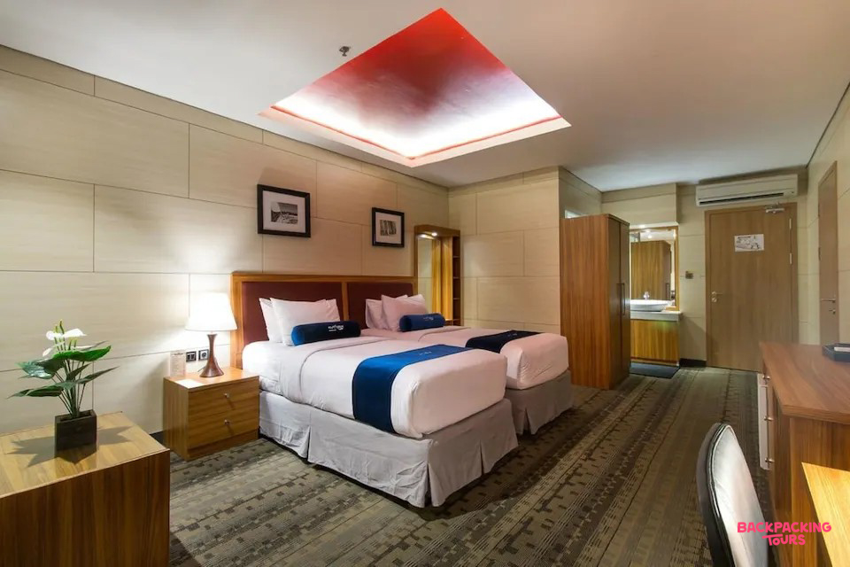 A modern hotel room in Kuta with two comfortable single beds and a stylish red ceiling light.