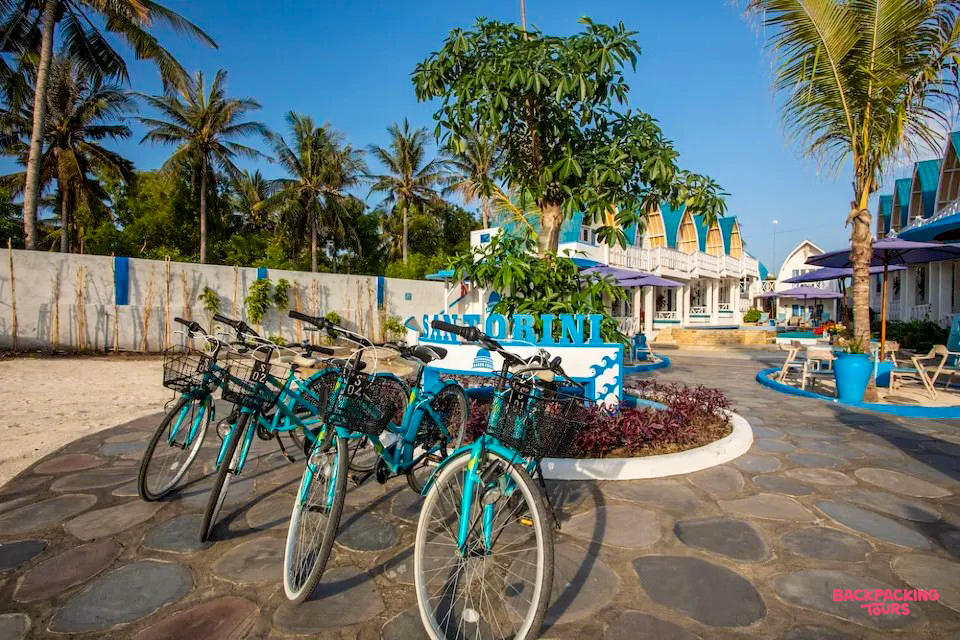 Blue bicycles parked in a sunny courtyard with white and blue buildings on Gili Trawangan.
