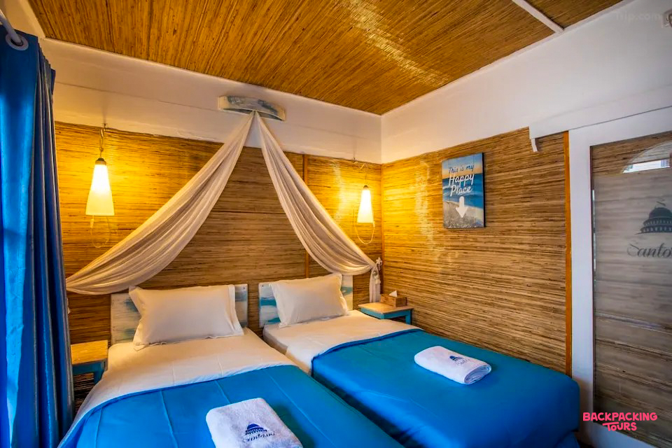 A cozy twin room with natural woven walls, blue accents, and a canopy bed at Gili Trawangan.