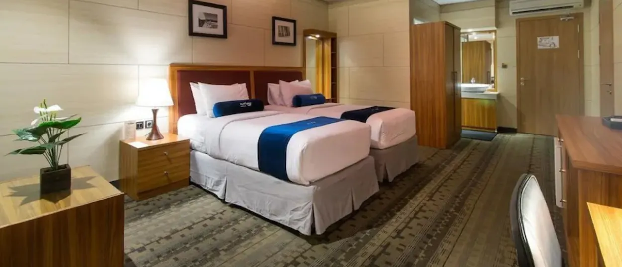 A clean and comfortable hotel room in Kuta with two single beds and modern furnishings.