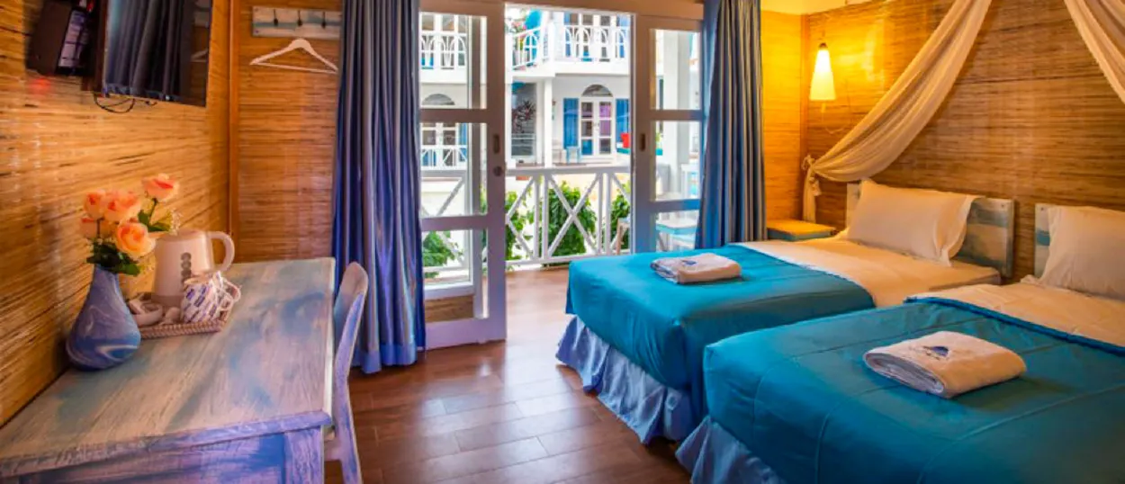 Relaxing twin room on Gili Trawangan featuring blue beds, natural decor, and a sunny balcony.
