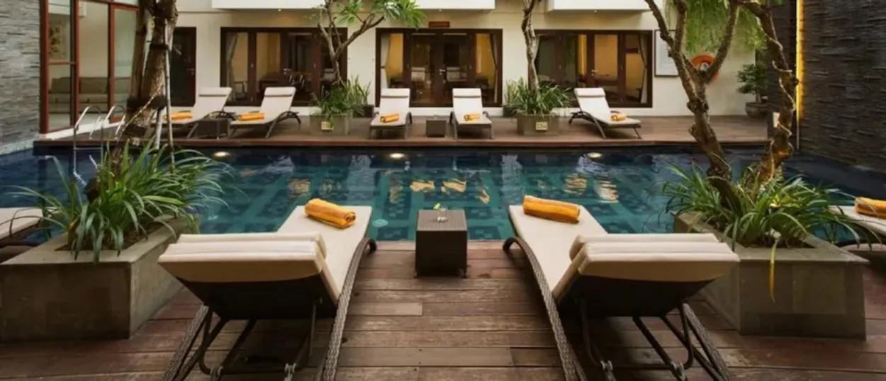 Relaxing hotel swimming pool with comfortable lounge chairs and lush plants in Seminyak, Bali.