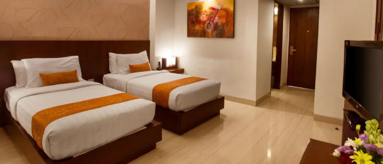 A modern hotel room in Seminyak, Bali, featuring two comfortable beds with orange accents.