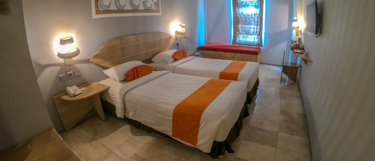 A bright hotel room in Canggu, Bali, featuring two single beds and a cozy window bench.