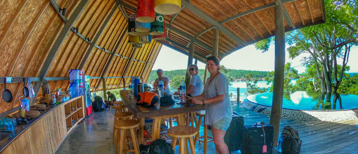 Smiling travelers enjoy a tropical open-air bar with ocean views on Nusa Lembongan, Bali.