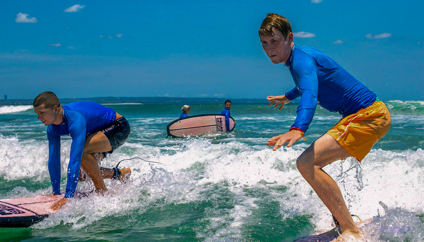 Enthusiastic backpackers learning to surf on the beautiful waves of Canggu, Bali.