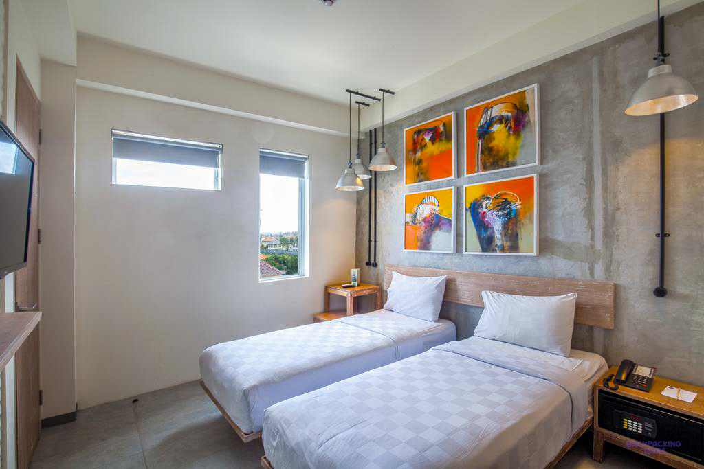 A comfortable hotel room in Canggu, Bali, with twin beds, a TV, and colourful abstract paintings.