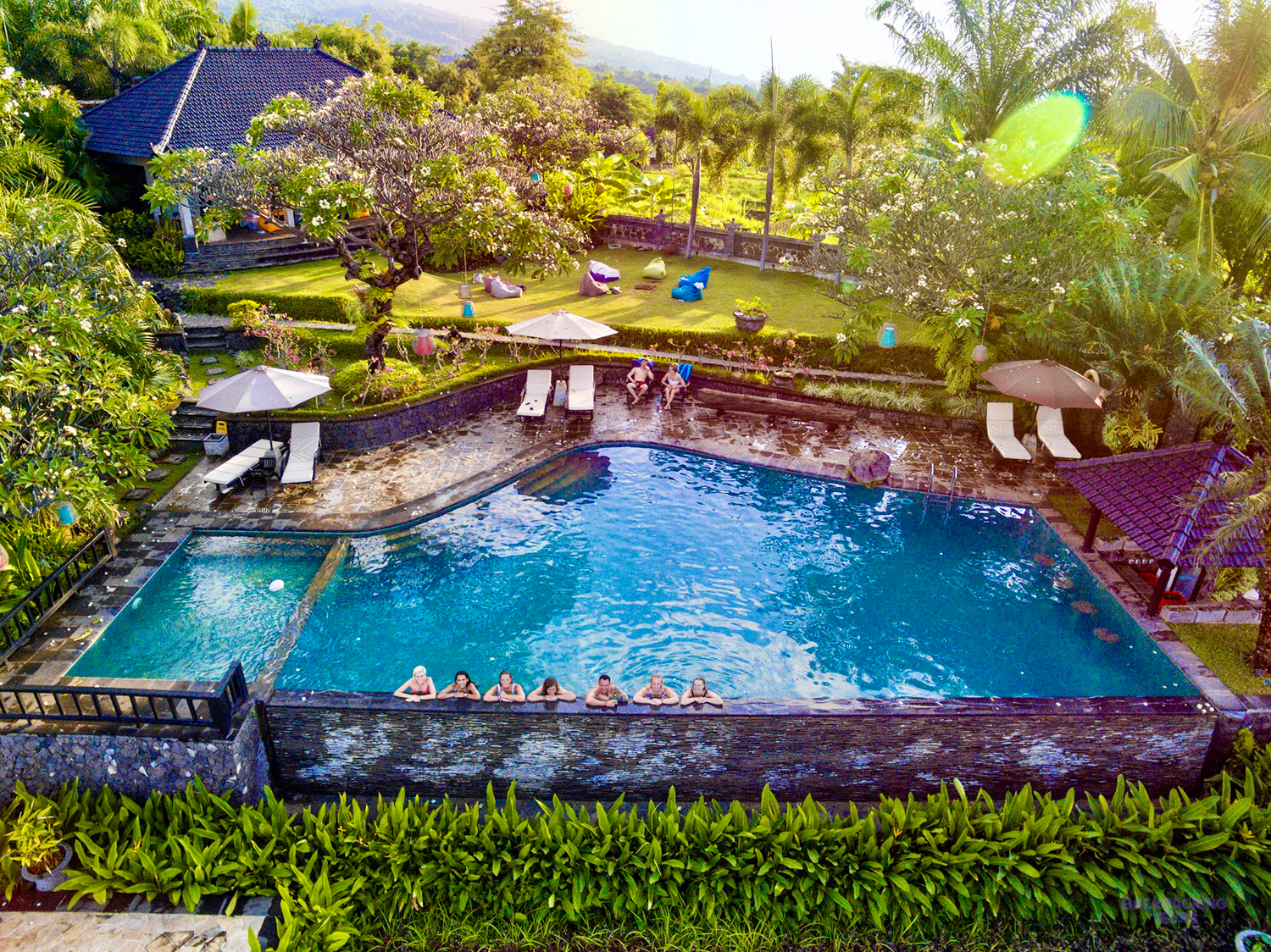 Friends relaxing by the beautiful pool at a mountain villa surrounded by lush greenery in Lovina.