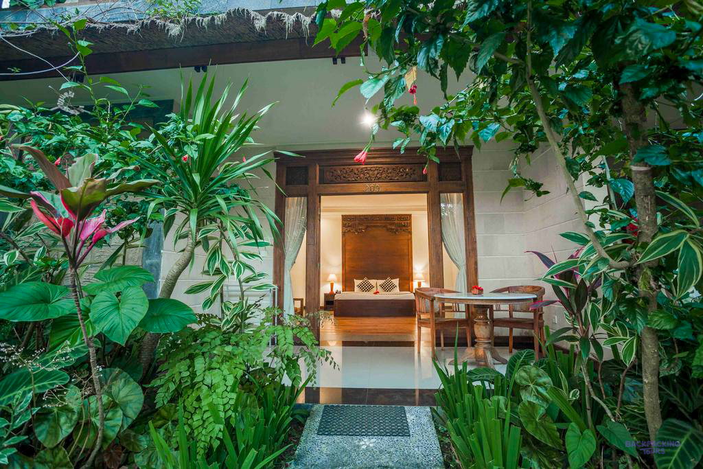 A tranquil guesthouse room in Ubud, Bali, featuring a comfortable bed and lush tropical garden.