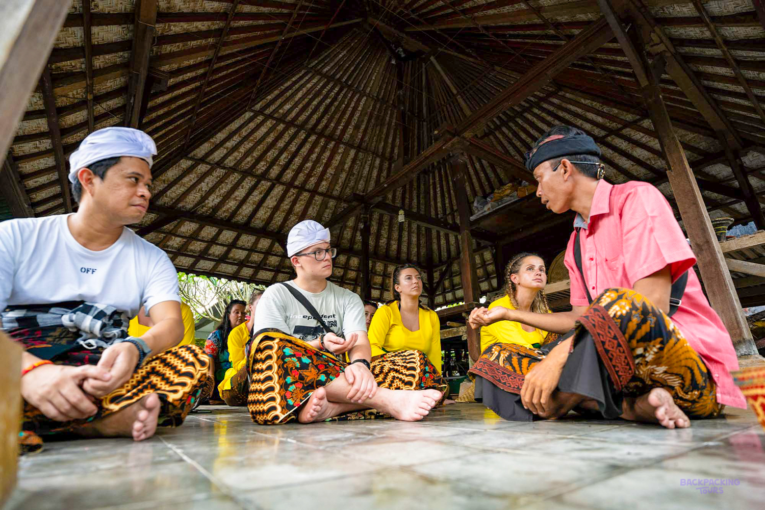 Travelers in traditional attire learn about Balinese culture during a local blessing ceremony in Canggu.