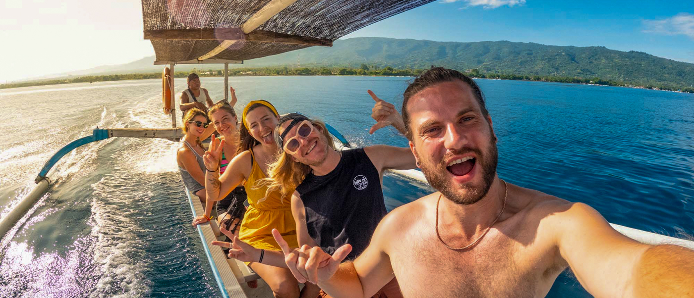 Smiling friends take a selfie on a traditional outrigger boat in Lovina, Bali, on the ocean.