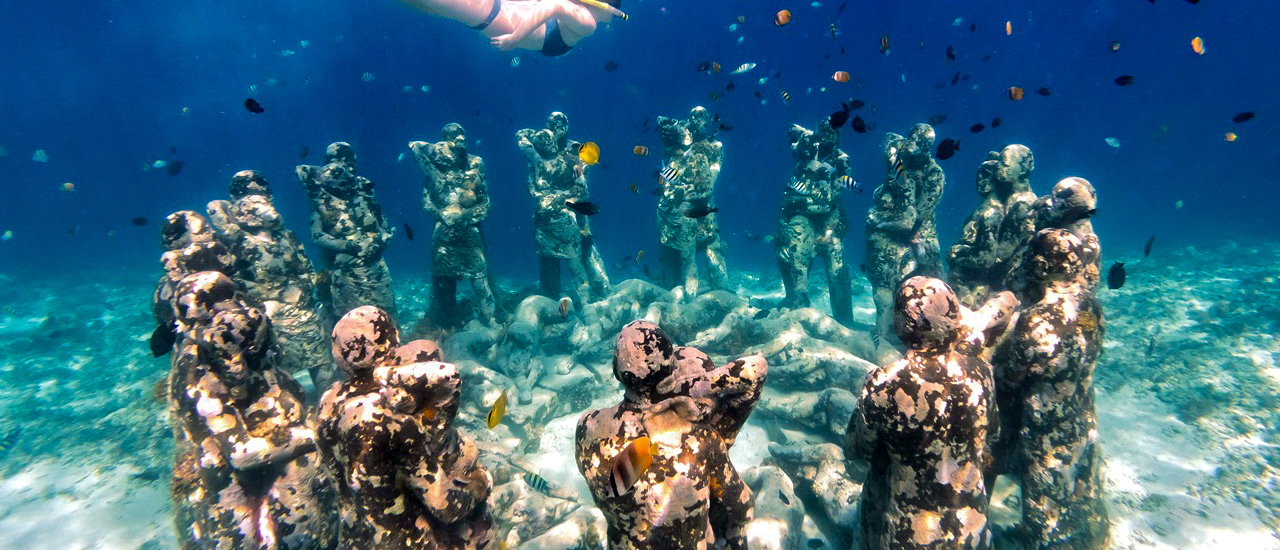 A snorkeler explores the captivating underwater 'Nest' statues and swimming fish at Gili Trawangan.