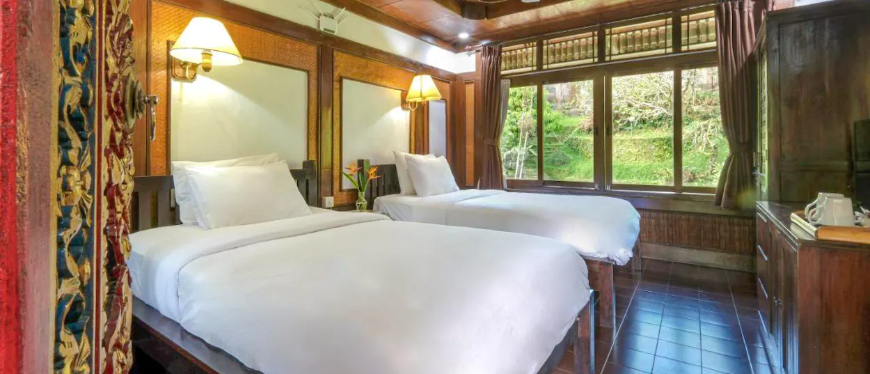 A cozy twin room with wooden decor and a lush green jungle view in Ubud, Bali.