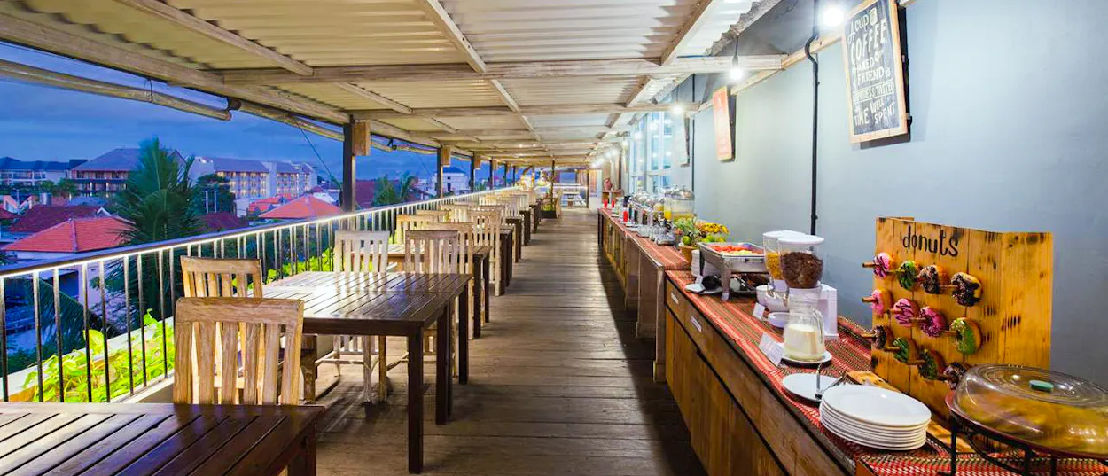 Rooftop restaurant in Canggu with a buffet line and empty tables, ready for a group dinner.