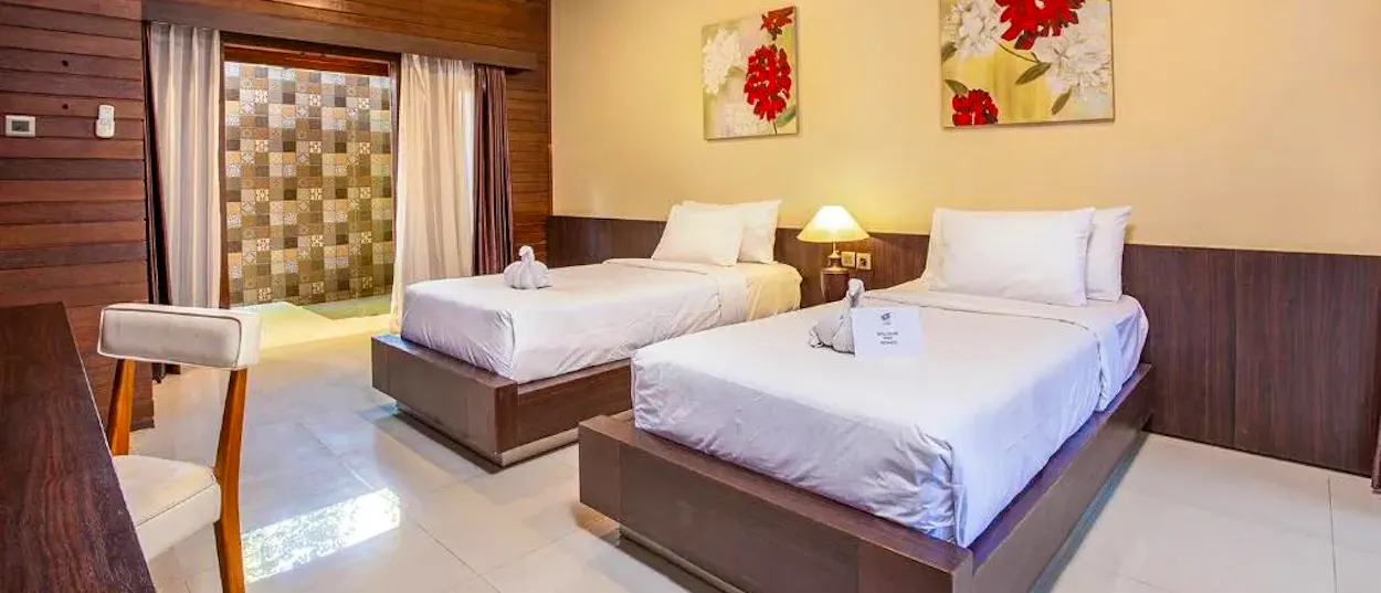 A clean hotel room on Gili Trawangan with two single beds and wooden accents.
