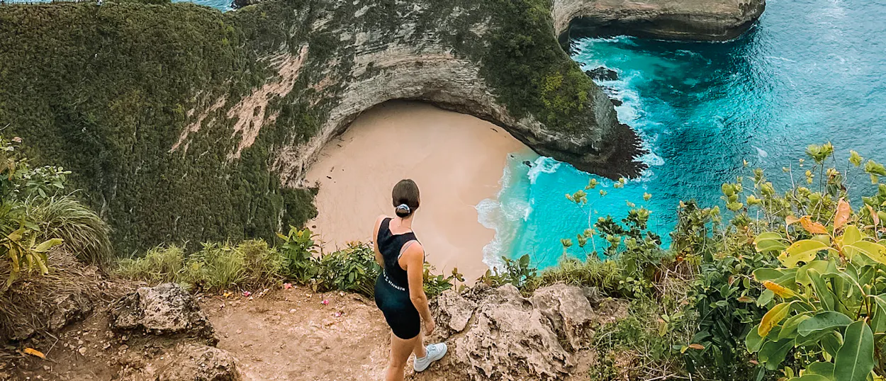 A woman overlooks the stunning T-Rex shaped Kelingking Beach with turquoise water in Nusa Penida.