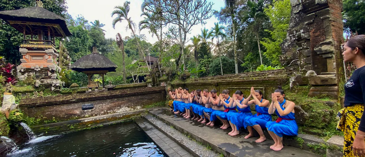Travelers in blue sarongs perform a purification ritual at Tirta Empul water temple in Ubud, Bali.