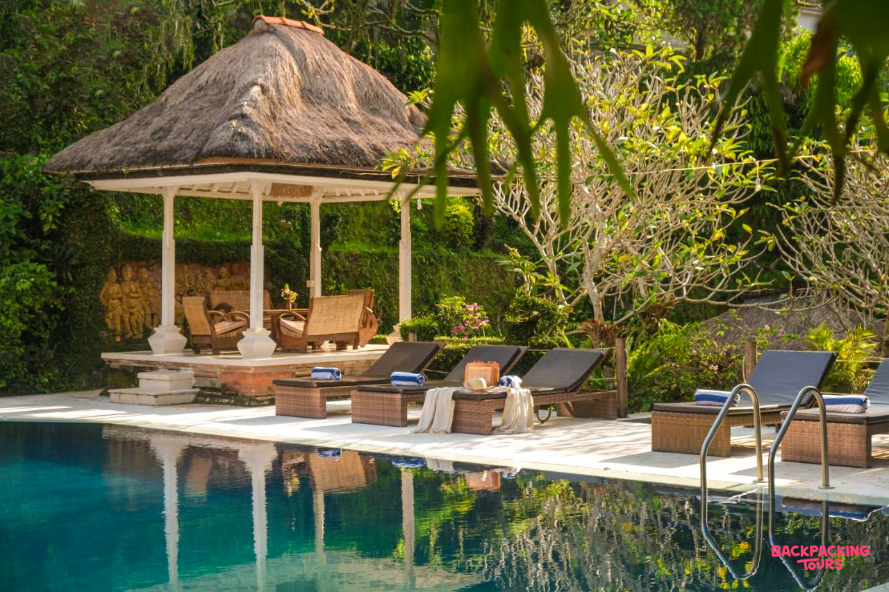 A serene swimming pool with sun loungers and a traditional thatched gazebo in Ubud, Bali.