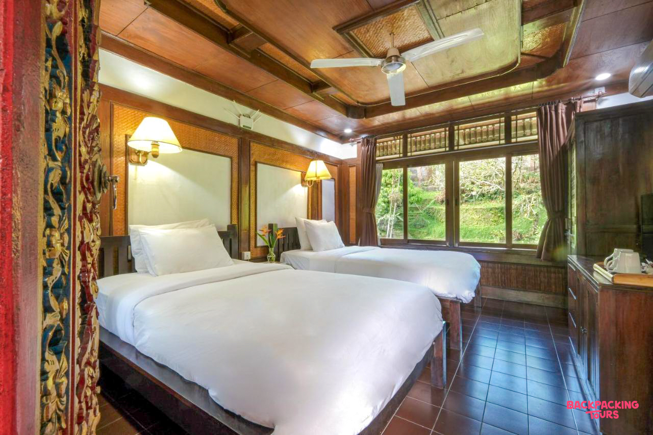 A cozy twin room in Ubud, Bali, with traditional wooden decor and a lush green view.