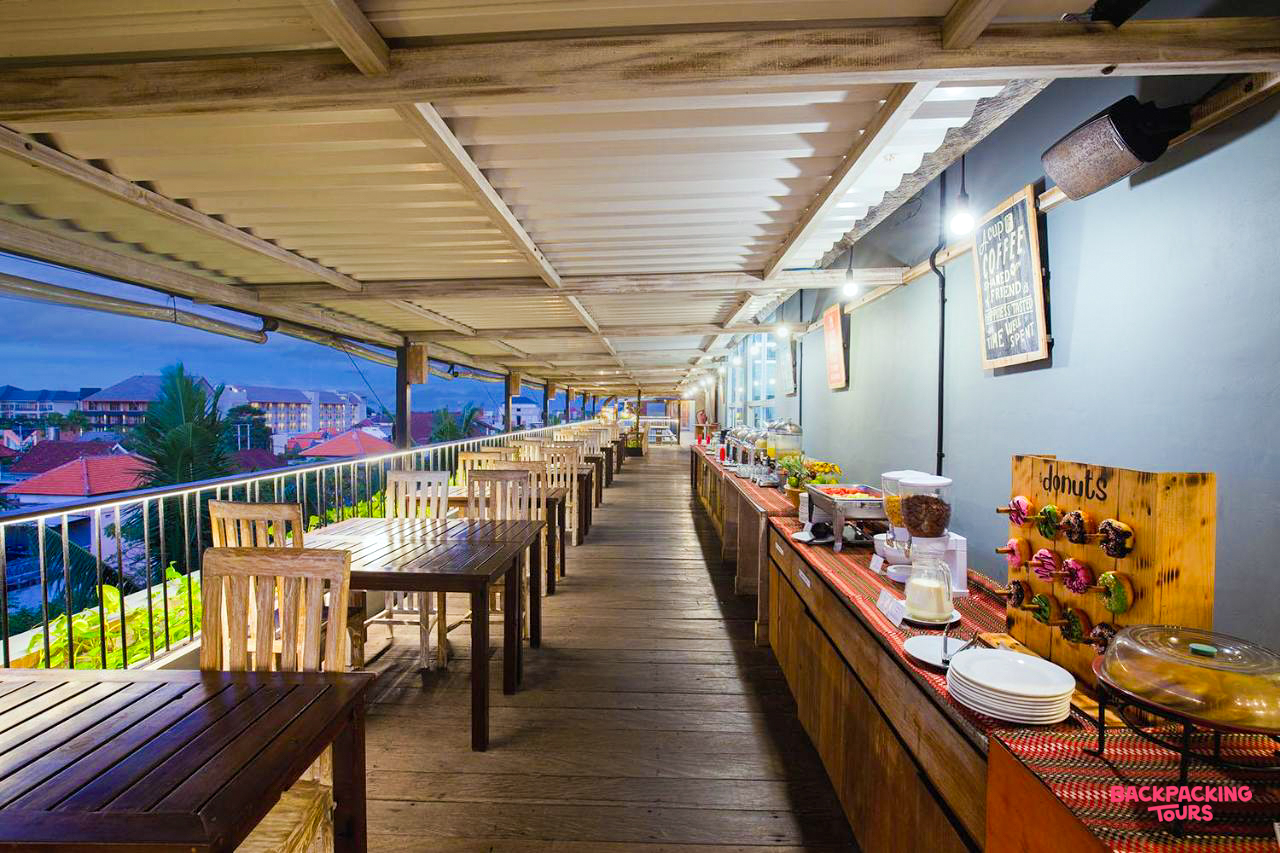 Evening view of a hotel rooftop restaurant in Canggu, Bali, featuring a buffet and empty tables.