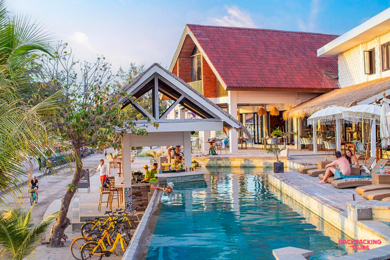 Guests relax by the pool and bar at a lively beachside resort on Gili Trawangan island.