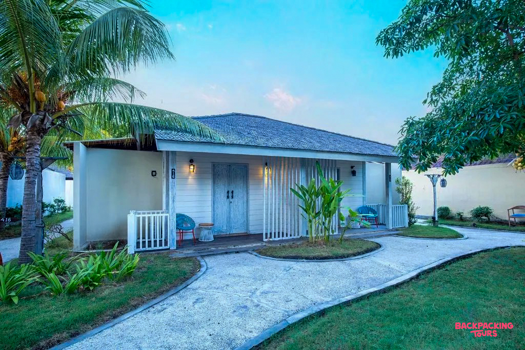 Inviting tropical bungalow with a private porch, surrounded by green lawns and palm trees on Gili Trawangan.