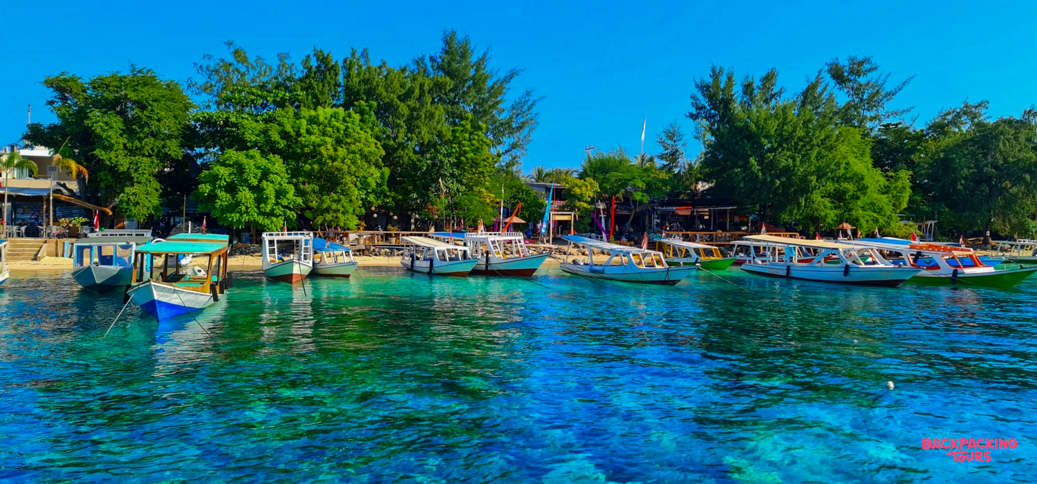 Small boats rest on the clear turquoise waters of a tropical beach in Pemuteran, Bali.