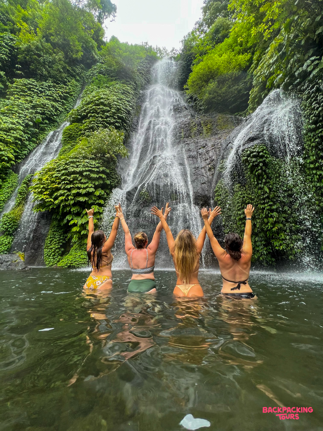 Four friends enjoy a refreshing swim at Banyumala Waterfall, surrounded by lush Balinese jungle.