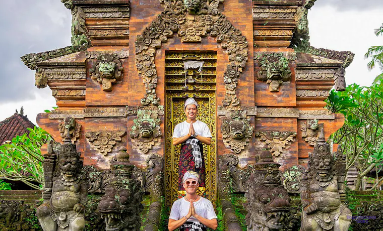 Two men in traditional Balinese dress pose at a beautifully carved ancient temple in Canggu.
