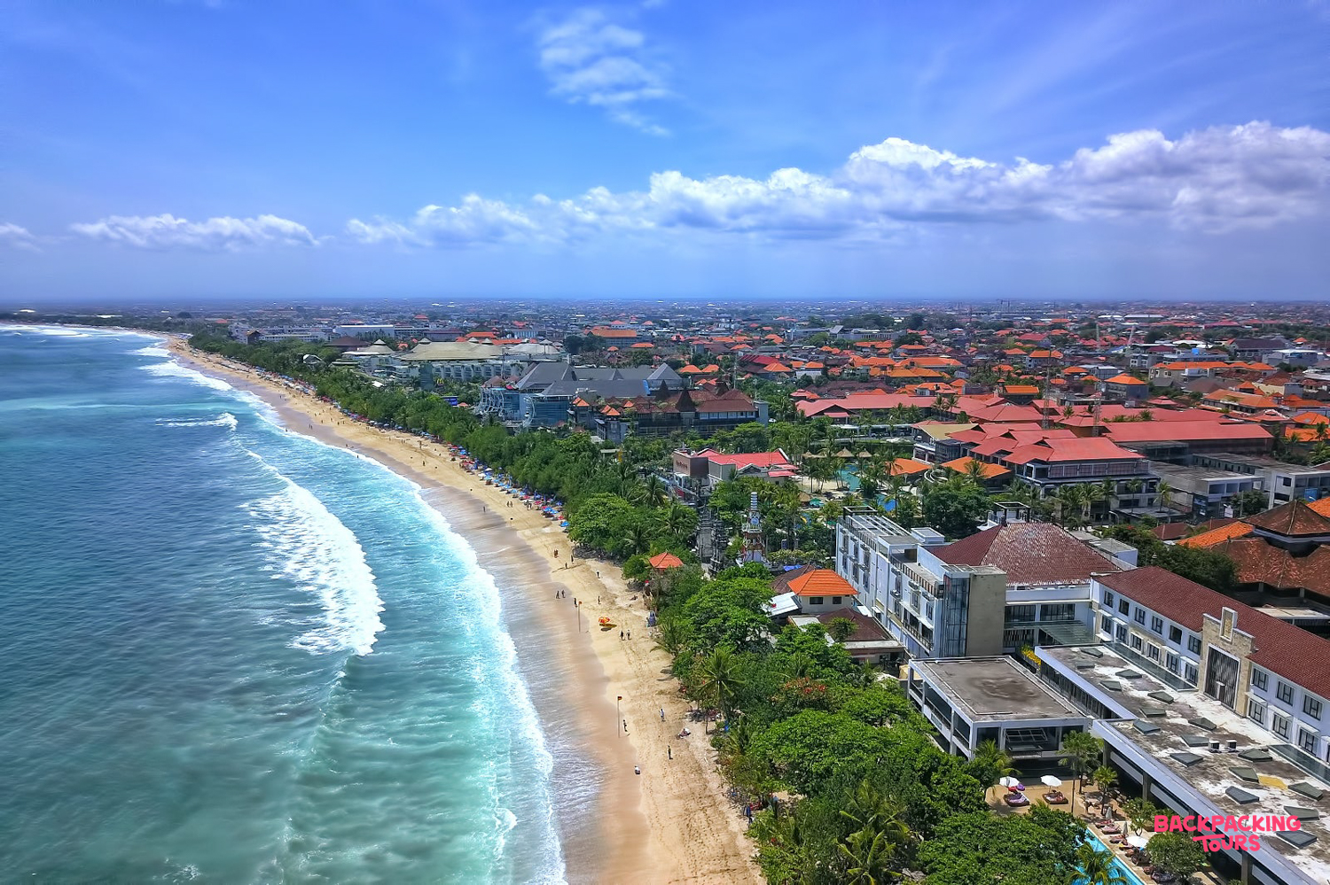 Stunning aerial view of Bali's vibrant coastline, featuring sandy beaches and a bustling town.