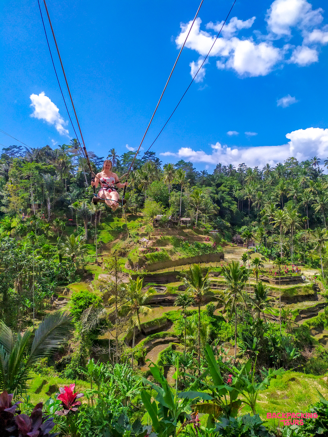 Smiling woman on a giant swing overlooking the stunning Tegallalang rice terraces in Ubud.