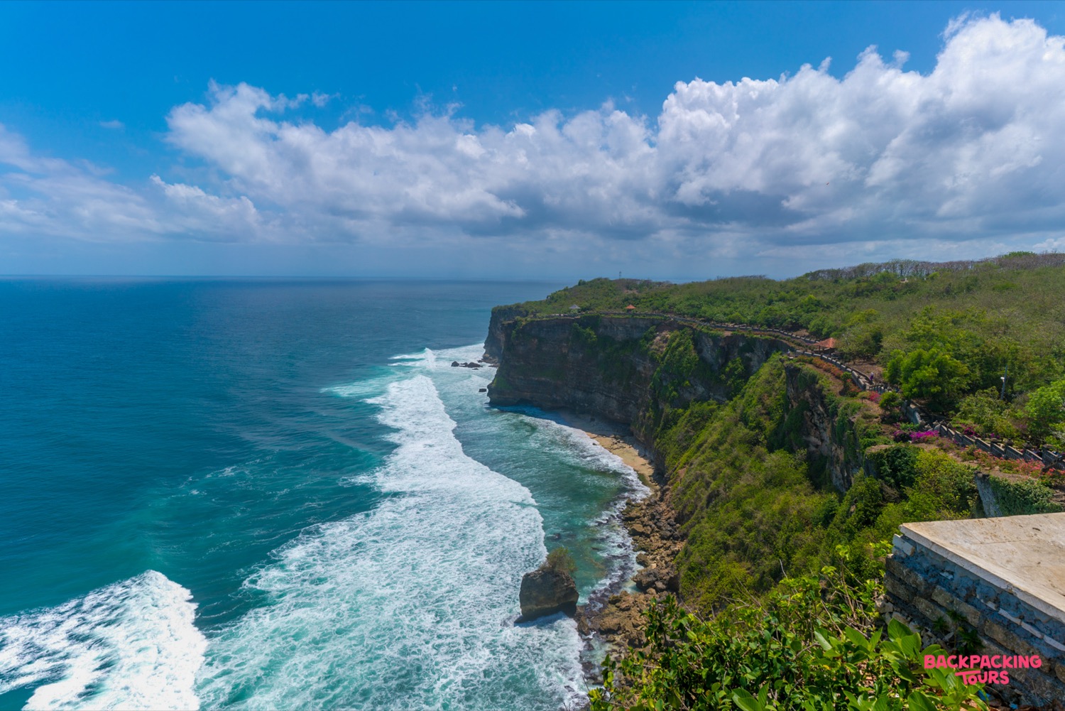 Majestic cliffs of Uluwatu plunge into the turquoise ocean, with waves crashing on Bali's scenic coastline.