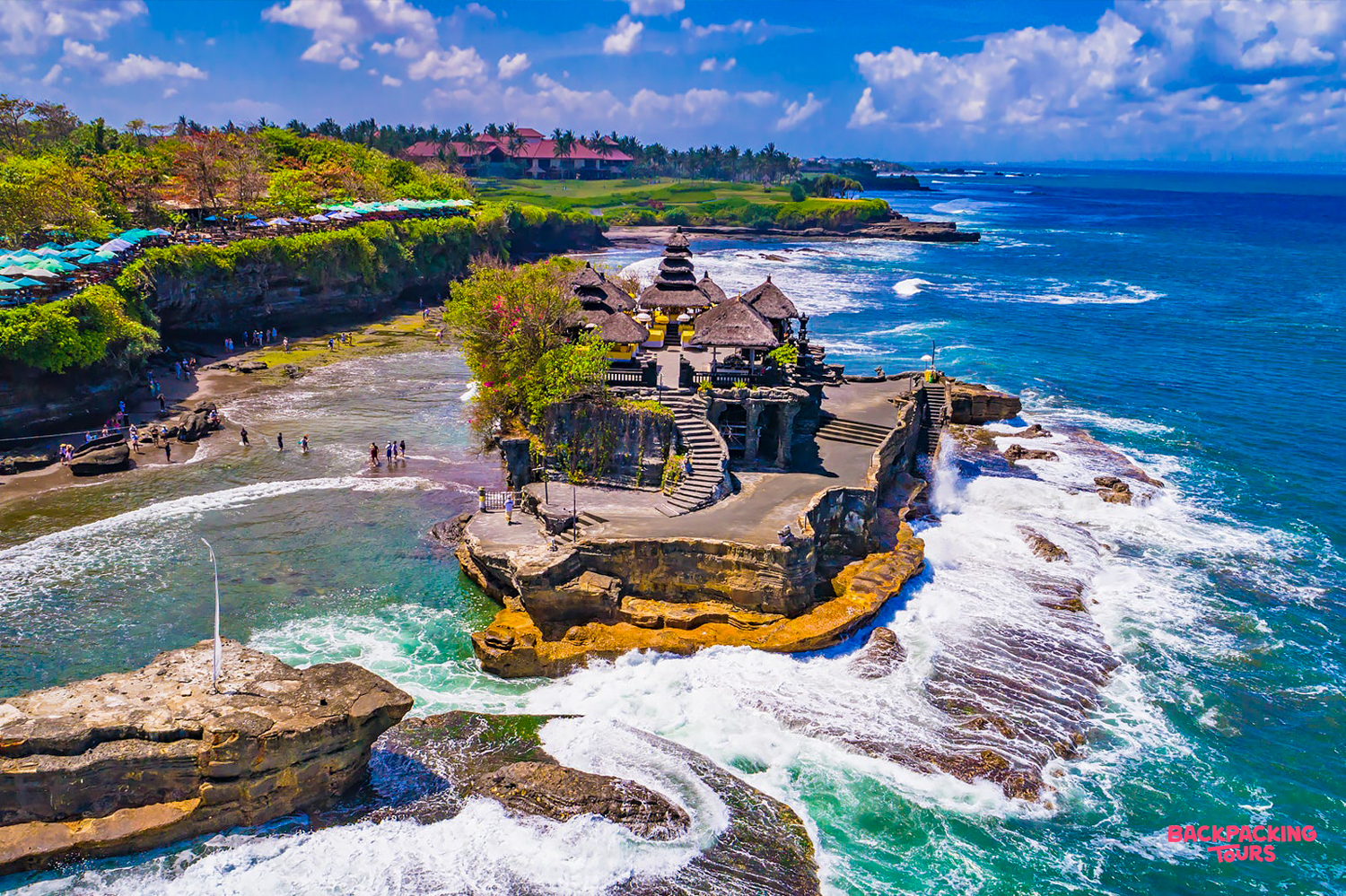 Balinese Tanah Lot temple on a rocky outcrop, surrounded by crashing waves and lush cliffs.