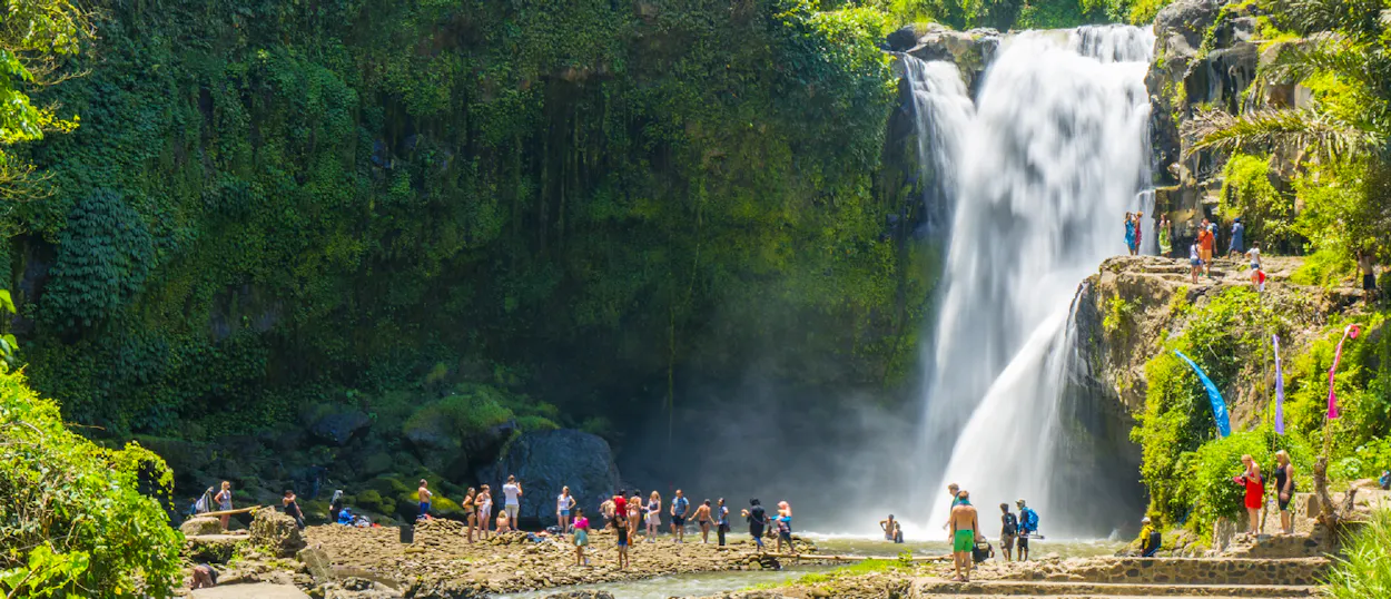 Travelers enjoy the powerful cascade of Tegenungan Waterfall, surrounded by lush jungle in Bali.