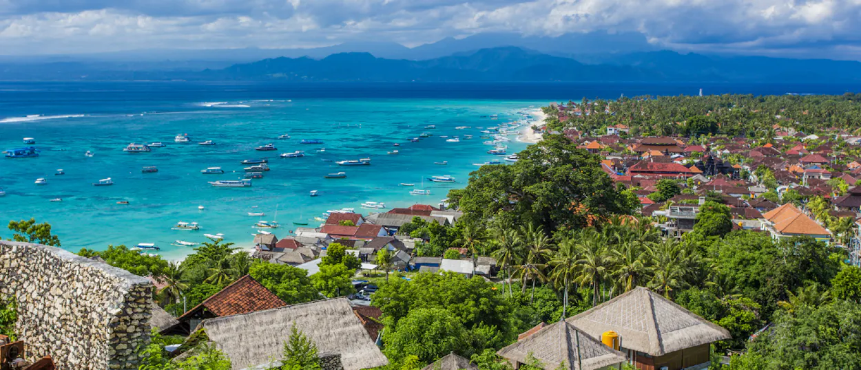 Panoramic view of Canggu, Bali, featuring a bustling beach, turquoise ocean, and lush tropical town.